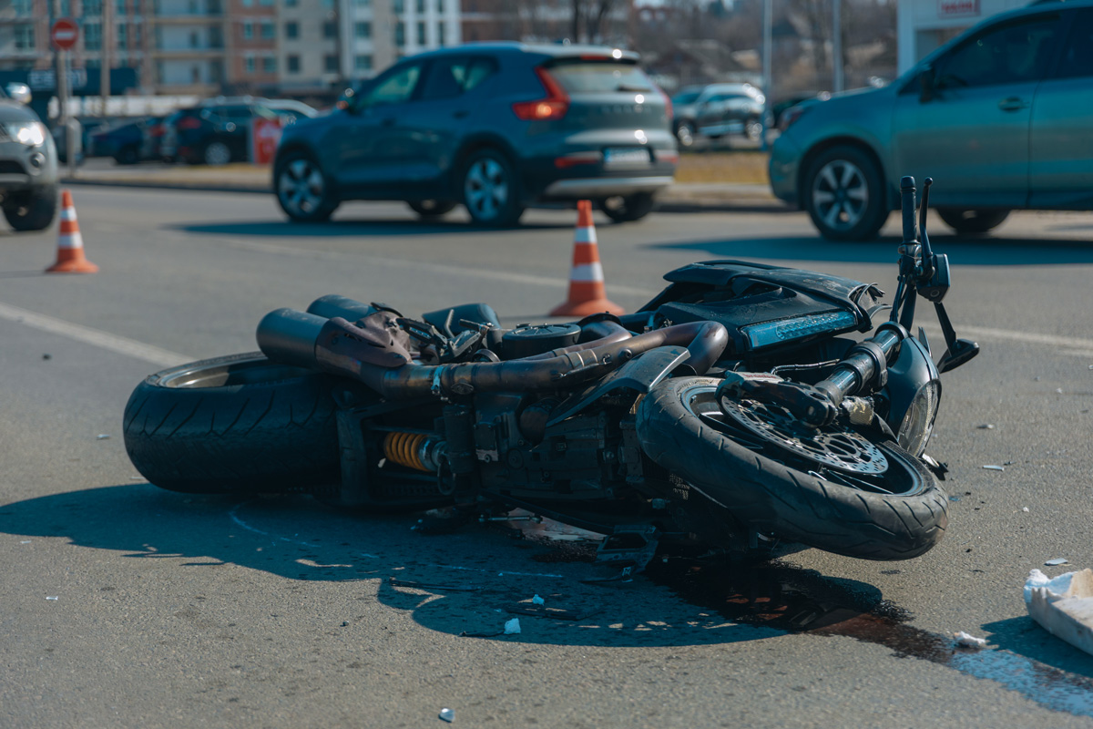 A crashed motorcycle lying on its side on the road.