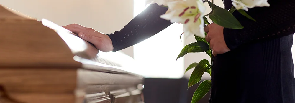Woman with lily flowers and coffin at funeral