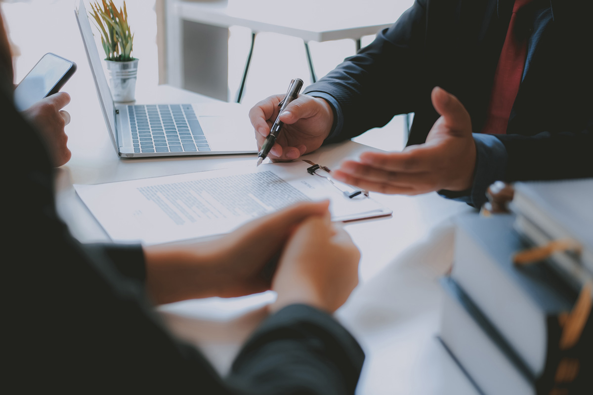 An estate planning lawyer and client sitting at a white desk talking in El Paso.