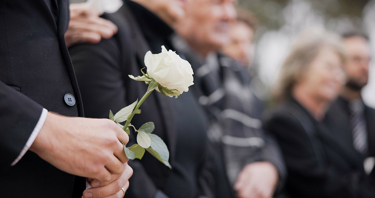 A person at a funeral holding a white rose in Missouri City.