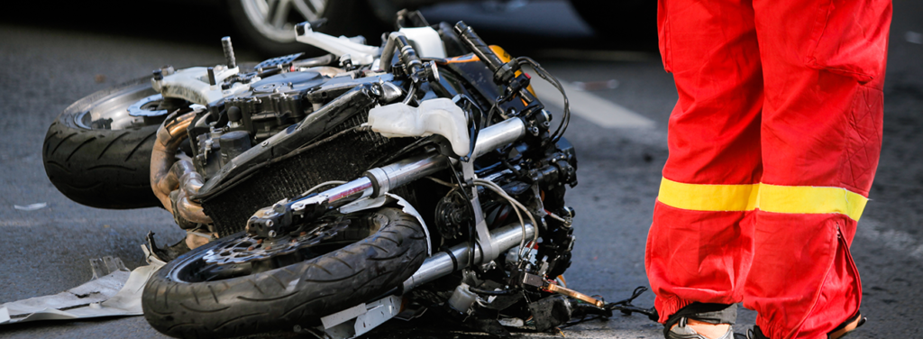 Crashed motorcycle after road accident with a car